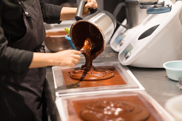 Konditor maakt chocolade dessert in een snoepwinkel.