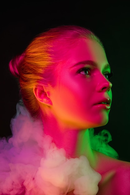 Koningin. Portret van vrouwelijke mannequin in neonlicht op donkere studioachtergrond met rook. Mooie blanke vrouw met trendy make-up en verzorgde huid. Levendige stijl, schoonheidsconcept. Detailopname.