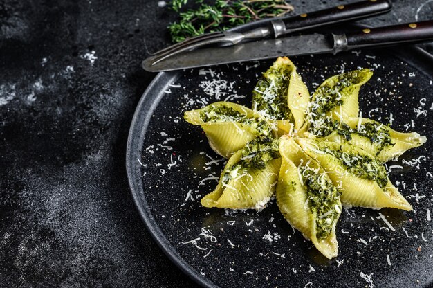 Konkiloni 이탈리아 점보 껍질 파스타 Conchiglioni는 접시에 쇠고기 고기와 시금치를 채워 넣었습니다.