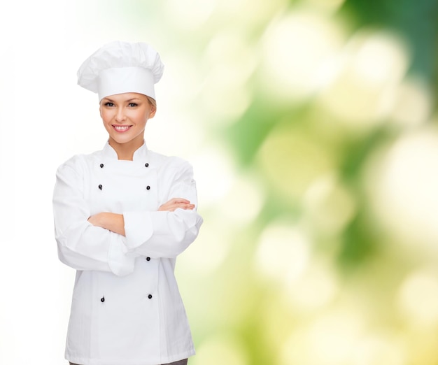 kook- en voedselconcept - glimlachende vrouwelijke chef-kok, kok of bakker met gekruiste armen
