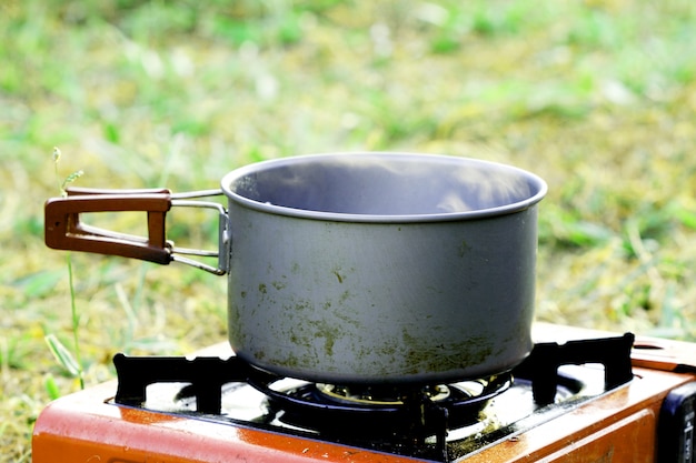 Kook iets in pot op een gasfornuis op gras om te kamperen