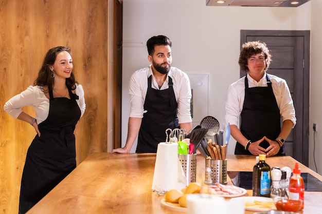 Kookcursus senior mannelijke chef-kok in kookuniform leert jongeren kooklesstudenten om ingrediënten voor gerechten in de keuken van het restaurant te bereiden en te mixen