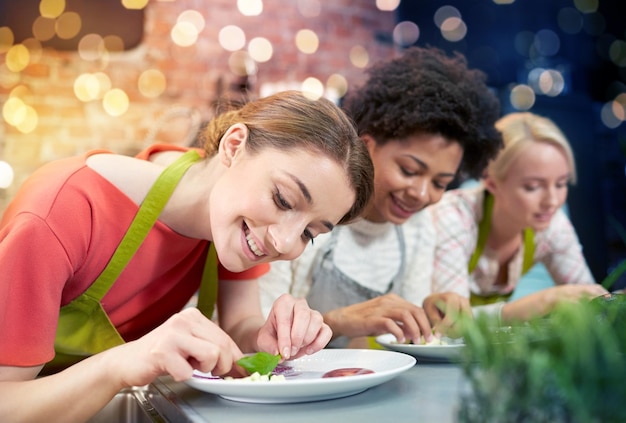 Foto kookles vriendschap voedsel en mensen concept gelukkige vrouwen koken en versieren borden met gerechten in de keuken