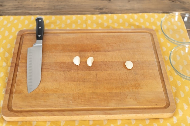 Kookplank met mes en drie teentjes knoflook ruimte kopiëren