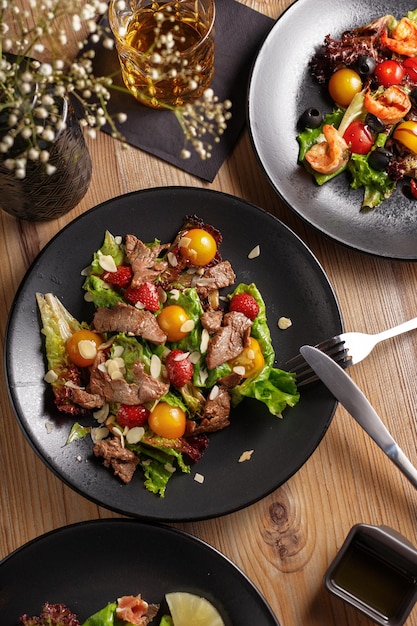 Kookschotel voorgerecht Salade Restaurant serveert zwarte gerechten houten tafel