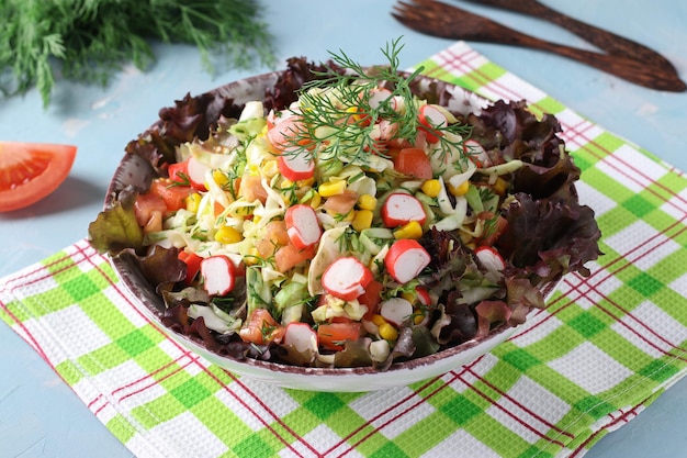 Koolsalade met krabsticks, tomaten en maïs geserveerd op slablaadjes