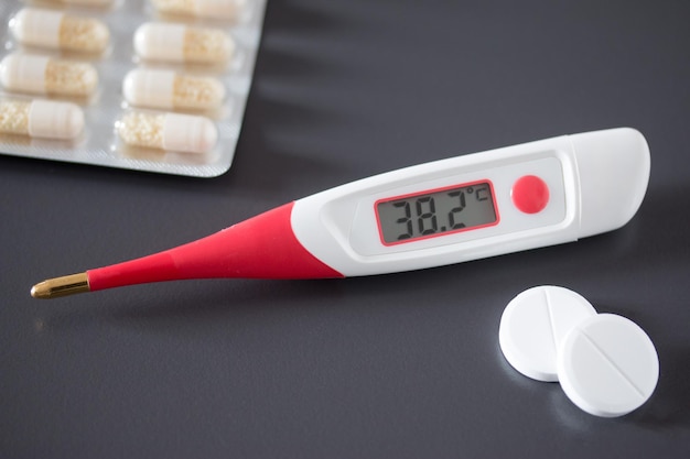 Koortsthermometer en pillen op het bureau 38 graden Celsius op het display