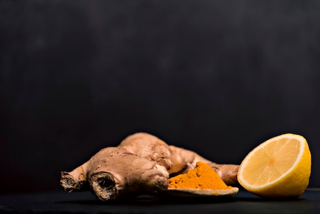 Kop hete thee met gemberwortel, citroen en curcuma die natuurlijke rauwe honing toevoegen aan een kopje hete thee vitamine