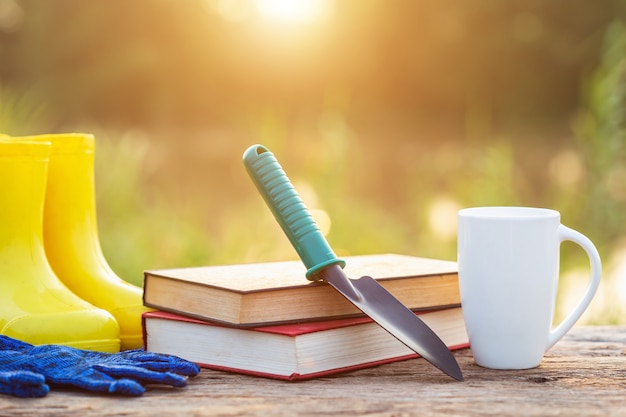 Kop koffie, boek, en tuinmateriaal op houten lijst met zonlicht in ochtendtijd