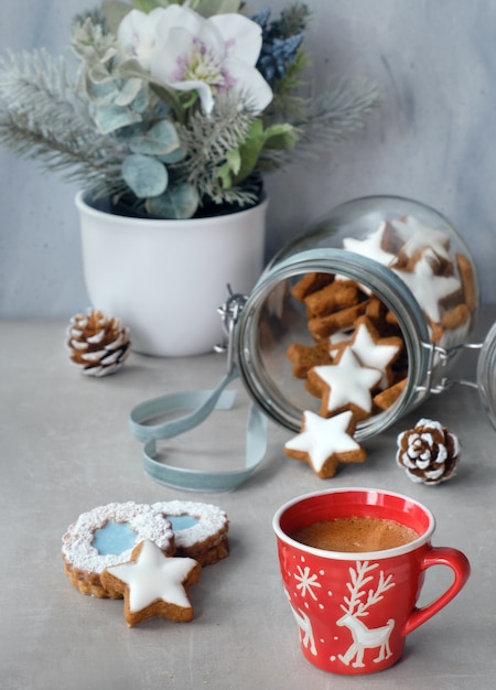 Kop koffie en smakelijke stergemberkoekjes in een glaskruik met de winterbloemen