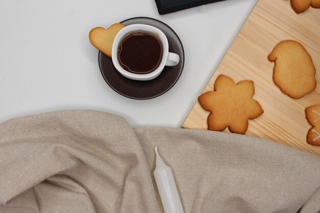 Foto kop koffie met een hartvormig koekje bruine tafeldoek witte kaars hout met kerstkoekjes