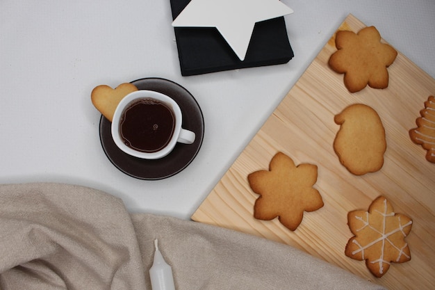 Foto kop koffie met hartvormig koekje bruin tafeldoek kaars servethouder kerstkoekjes