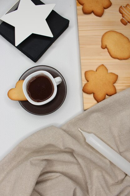 Foto kop koffie met hartvormig koekje bruin tafeldoek kaars servethouder kerstkoekjes