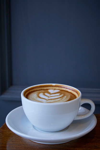 Kop van koffie latte kunst op het houten bureau