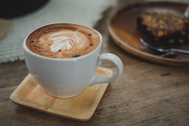 Kop van lattekoffie met browniecake op houten lijst