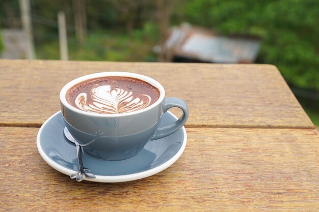 Kop warme chocolademelk latte art op houten tafel.