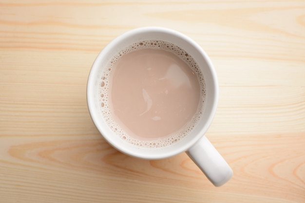 Kop warme chocolademelk met melk staat op houten tafel