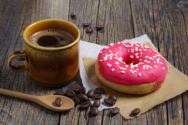 Kop warme koffie en aardbeidoughnut voor ontbijt op houten tafel