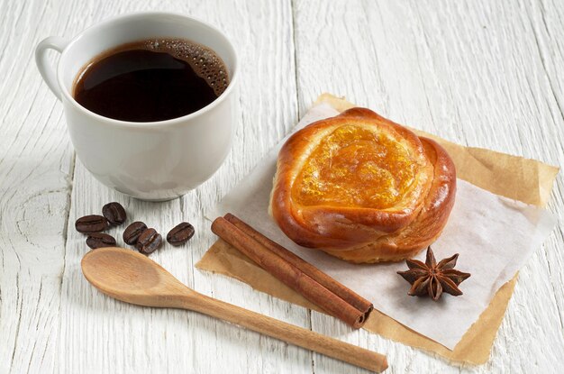 Kop warme koffie en broodje met jam op witte houten tafel