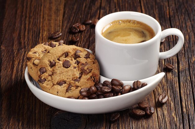 Kop warme koffie en chocoladekoekjes op donkere houten tafel