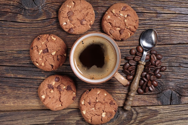 Kop warme koffie en heerlijke chocoladekoekjes op oude houten tafel, bovenaanzicht