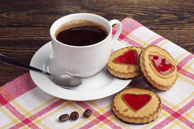 Kop warme koffie en koekjes met jam op rood tafelkleed