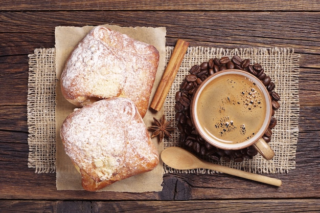 Kop warme koffie en twee verse broodjes op donkere houten tafel. Bovenaanzicht