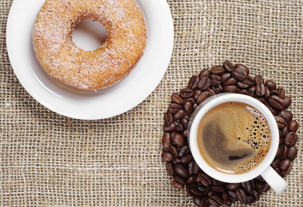 Kop warme koffie en zoete donut op een juteachtergrond