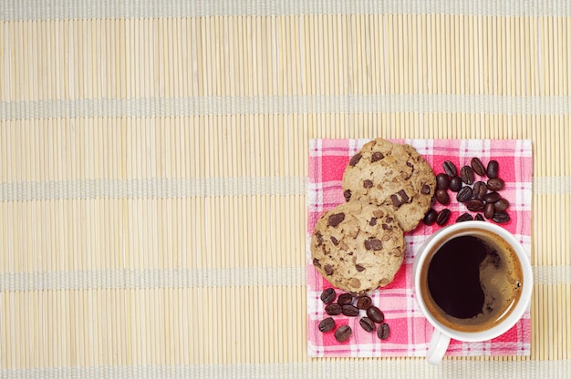 Kop warme koffie met chocoladekoekjes op een bamboe servet, bovenaanzicht