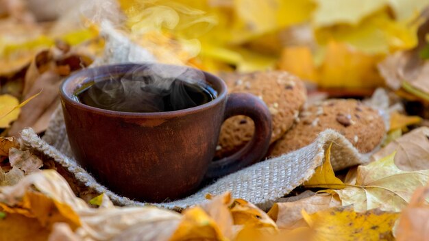 Kop warme koffie of thee en koekjes op geel de herfstblad