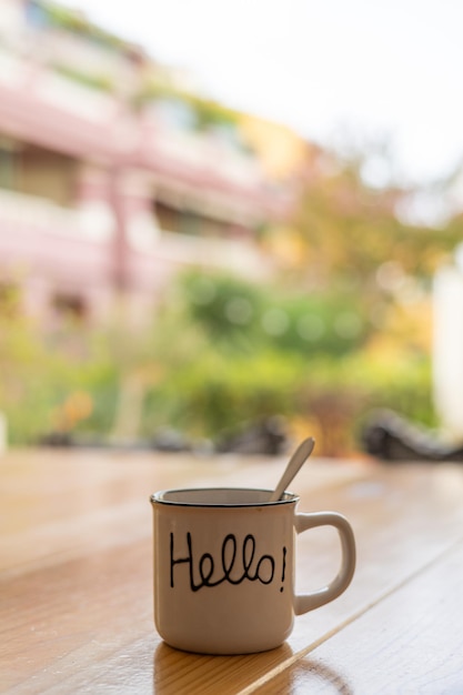 Foto kop warme koffie op een houten tafel buiten het huis met een bericht met het woord hallo