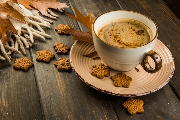Kop warme koffie op kerstmis en zoete koekjes, plaid met bruin eikenbladeren bovenaanzicht op houten achtergrond