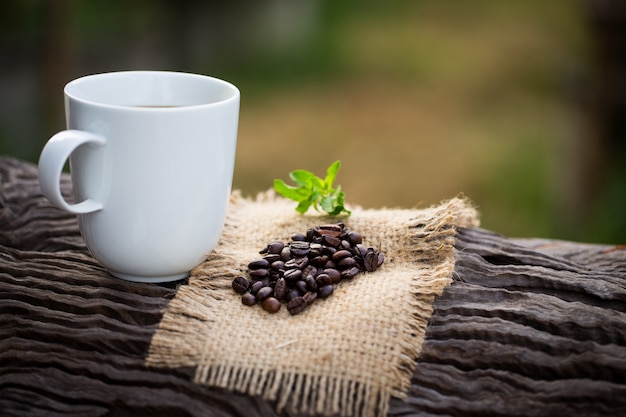 Kop zwarte koffie en koffiebonen op houten achtergrond.