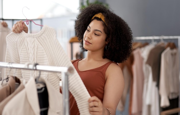 Kopen of niet kopen Shot van een jonge vrouw die kleding zoekt in een winkel