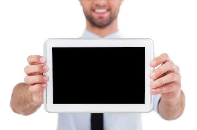 Kopieer ruimte op digitale tablet. Bijgesneden afbeelding van een vrolijke jonge man in formalwear die zijn digitale tablet laat zien en glimlacht terwijl hij geïsoleerd op een witte achtergrond staat