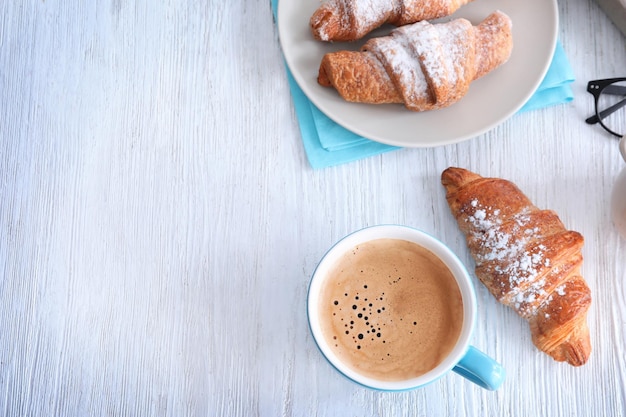 Kopje aromatische koffie in de ochtend en croissants op houten tafel