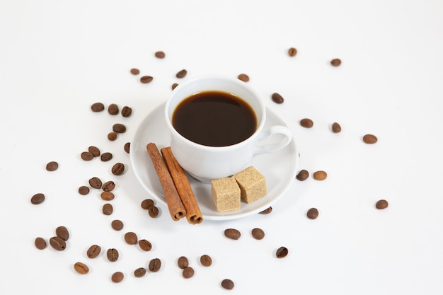 Kopje aromatische koffie op een witte achtergrond met suiker, kaneel en koffiebonen
