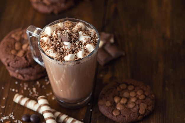 Kopje cacao met marshmallows en chocoladeschilferkoekjes op donkere houten ondergrond