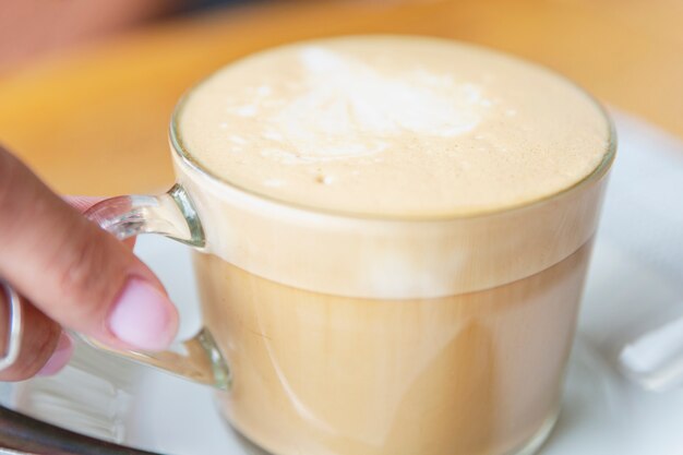 Kopje cappuccino koffie in vrouwelijke handen aan een tafel in een café. Bovenaanzicht.