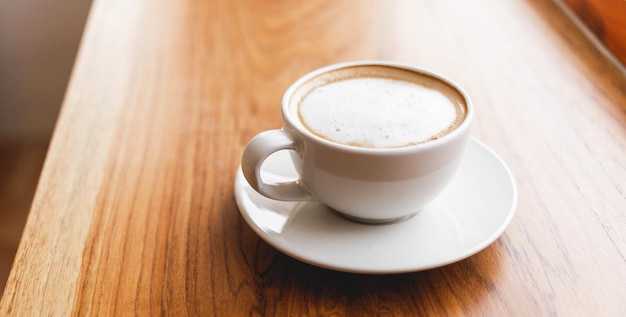 Kopje cappuccino-koffie met een latte op een houten bar in een zonovergoten café in de ochtend