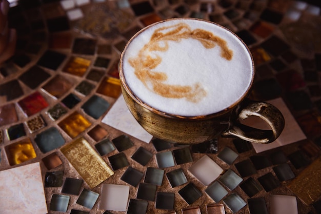 Kopje cappuccino koffie op een gekleurde glazen tafel in café