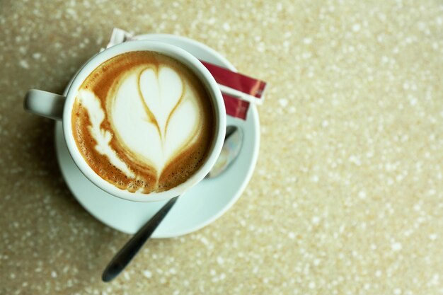 Kopje cappuccino met hart op schuim op tafel in café