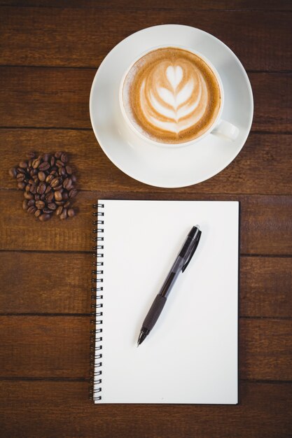 Kopje cappuccino met koffie kunst en Kladblok