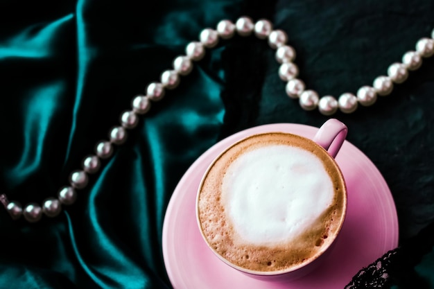 Kopje cappuccino voor ontbijt met satijn en parels sieraden achtergrond biologische koffie met lactosevrije melk in parijs café voor luxe vintage vakantiemerk