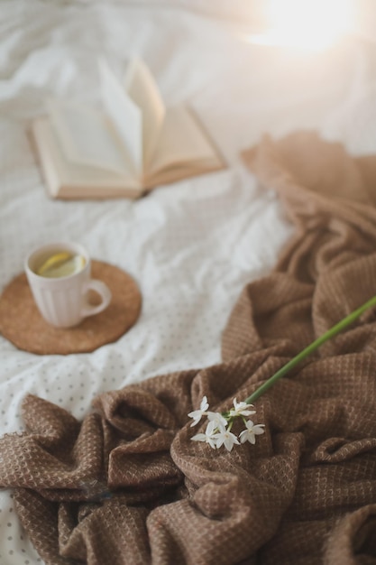 Kopje citroenthee narcisbloem en een boek over bed ontbijt op bed ochtend lente