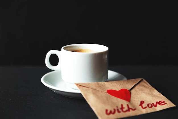 Kopje espressokoffie met valentijn. Zwarte achtergrond, selectieve aandacht.