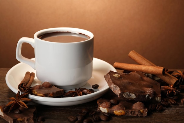 Kopje heerlijke warme chocolademelkkruiden en koffiebonen op houten tafel