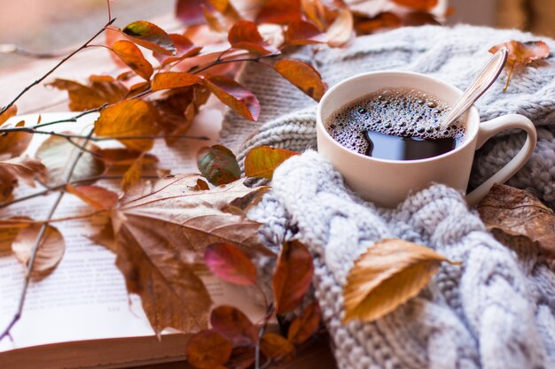 Foto kopje hete dampende koffie en een oud boek op de houten tafel