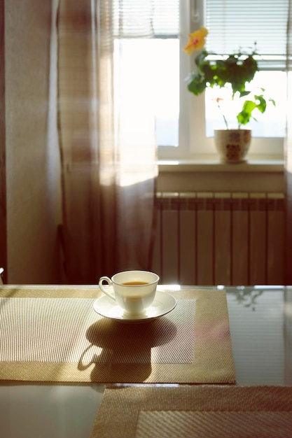 Kopje hete dampende koffie op een zonnige ochtend op de keukentafel