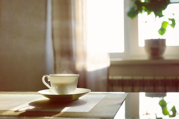 Kopje hete dampende koffie op een zonnige ochtend op de keukentafel